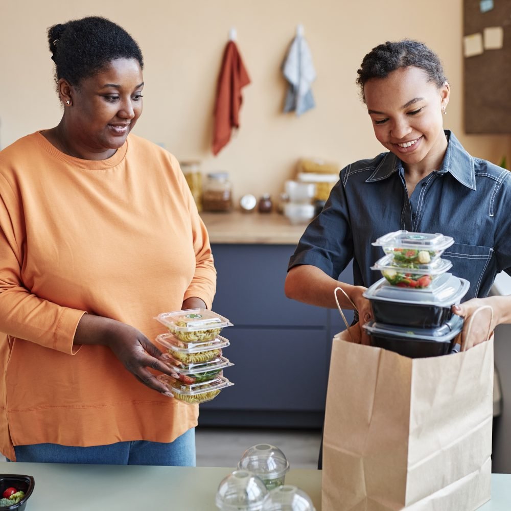 Waist up portrait of two African American women unpacking food delivery order at home